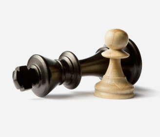 pawn in front of a knocked over king chess piece
